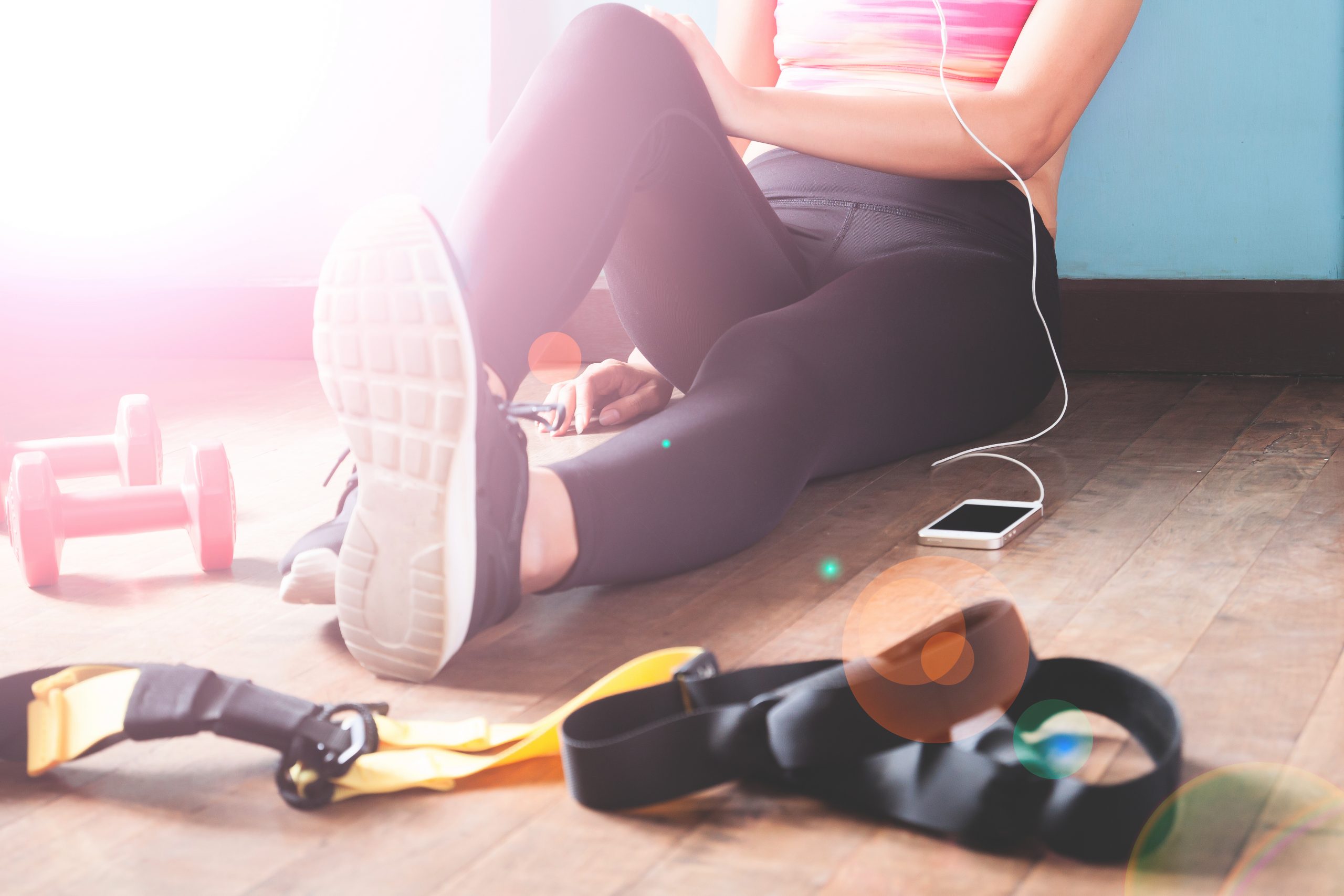 Female fitness resting and relaxing after workout. Woman sitting down on wood floor